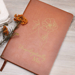 Havijo Unapologetically Me leather journal accessory with textured brown cover and stitched edges, open to reveal blank pages.